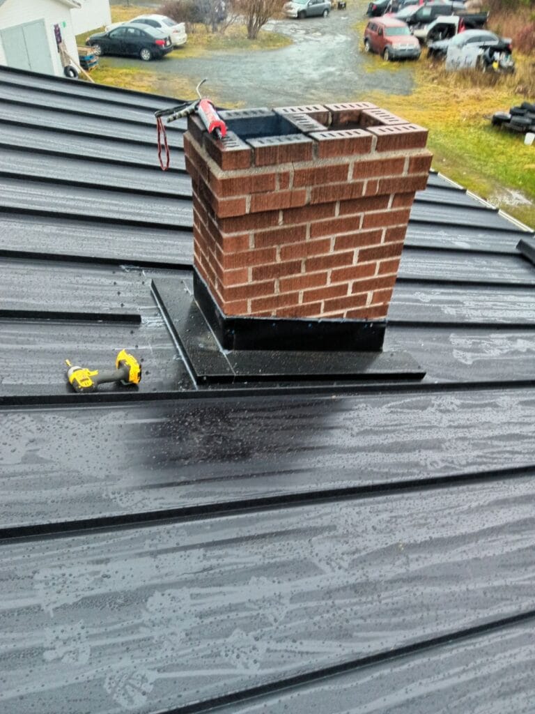 Black steel roof with brick chimney installed by Freedom Metal Roofing NL
