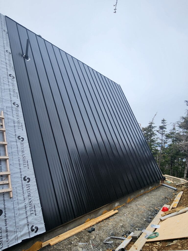 Black steel roof with vent pipe on one side of an A-frame installed by Freedom Metal Roofing NL
