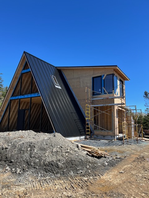Black steel roof with A-frame section, multiple flat lower levels, and skylight installed by Freedom Metal Roofing NL
