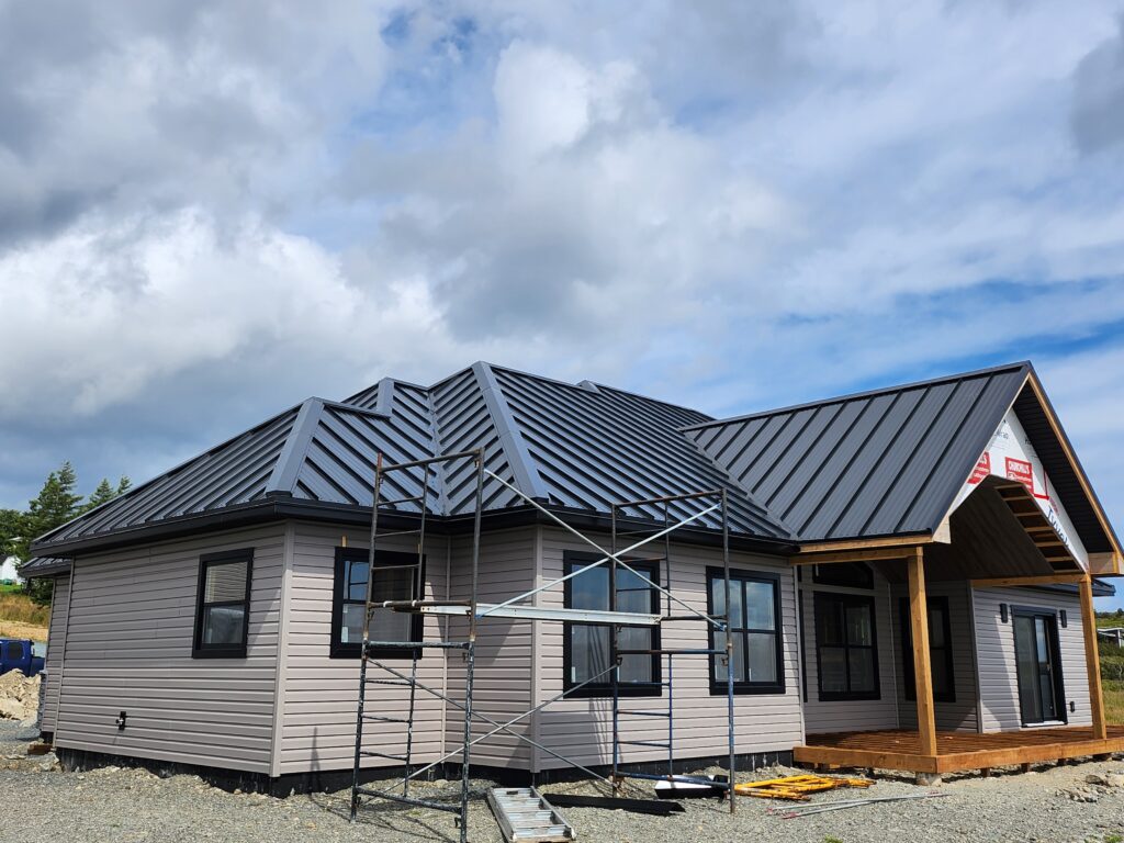 One-story house with multiple roof peaks and valleys, scaffold set up, steel roof installation by Freedom Metal Roofing NL
