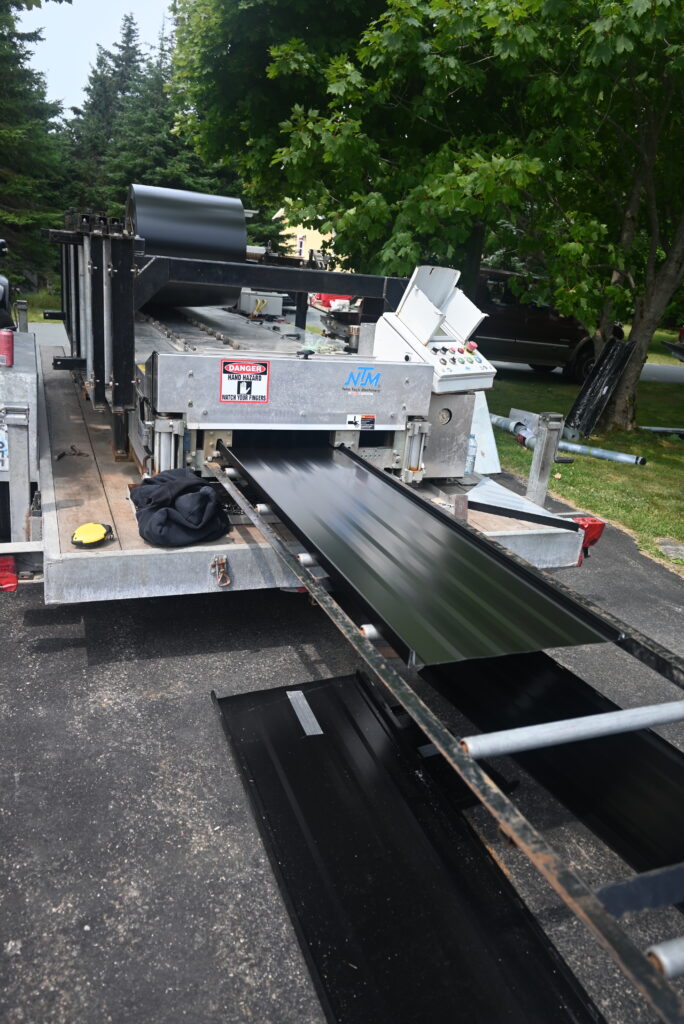 Mobile metal roofing panel machine fabricating panels on-site at Freedom Metal Roofing NL

